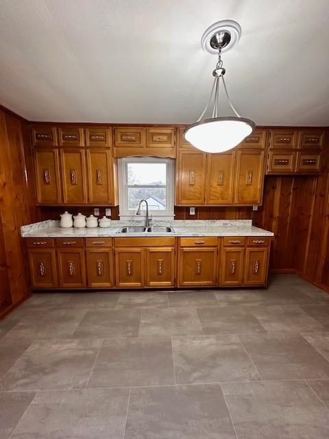 kitchen featuring sink, pendant lighting, and wooden walls