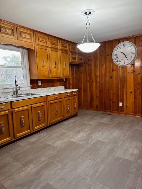 kitchen with sink, decorative light fixtures, and wood walls