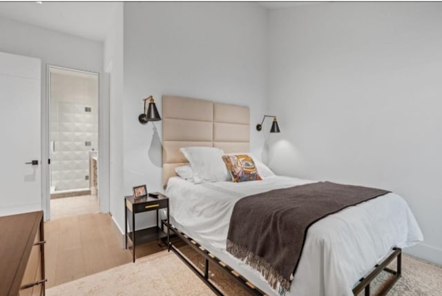 bedroom featuring connected bathroom and light hardwood / wood-style flooring