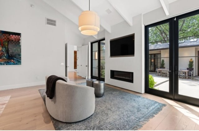 living room featuring light hardwood / wood-style flooring, high vaulted ceiling, and beamed ceiling