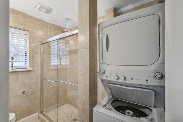 bathroom with walk in shower, stacked washer and clothes dryer, and toilet