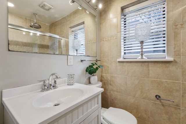 bathroom with plenty of natural light, toilet, a shower with door, and vanity