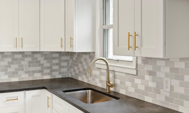 kitchen with dark countertops, white cabinets, and a sink