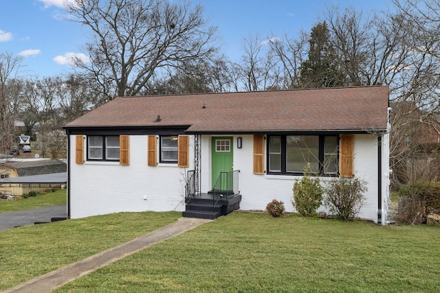 ranch-style house with a shingled roof, a front lawn, and brick siding