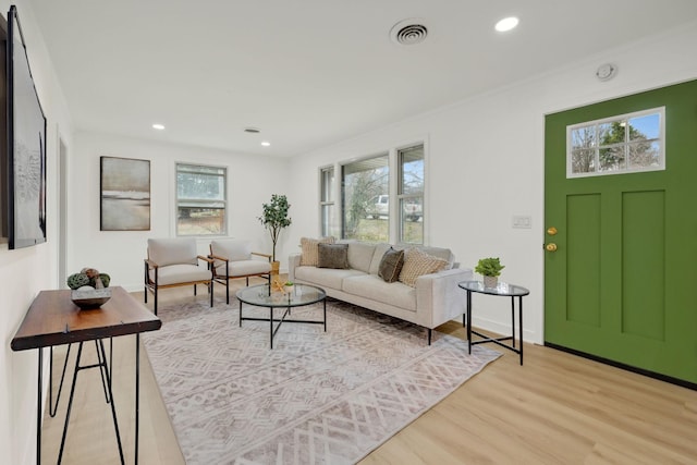 living room featuring light wood-type flooring, visible vents, crown molding, and recessed lighting