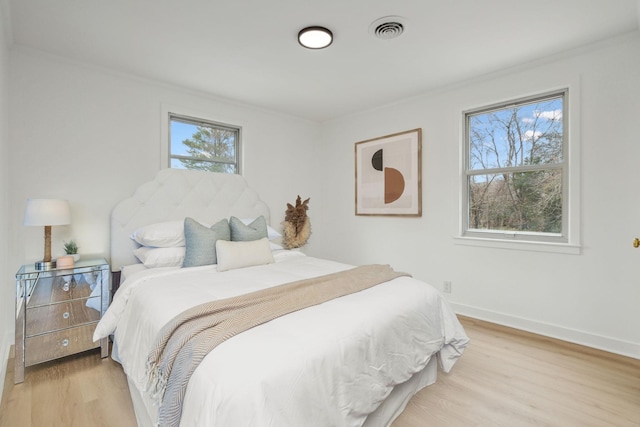 bedroom with light wood-type flooring, visible vents, and baseboards