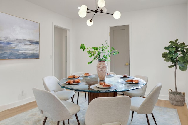 dining space featuring light wood-style floors, baseboards, and an inviting chandelier