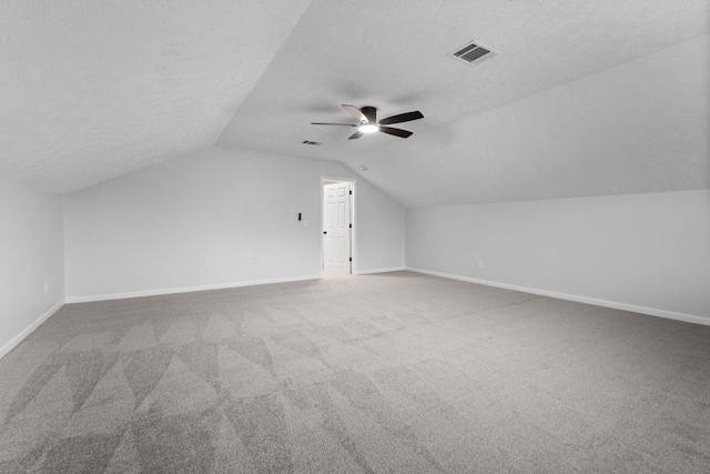 additional living space featuring vaulted ceiling, carpet flooring, ceiling fan, and a textured ceiling