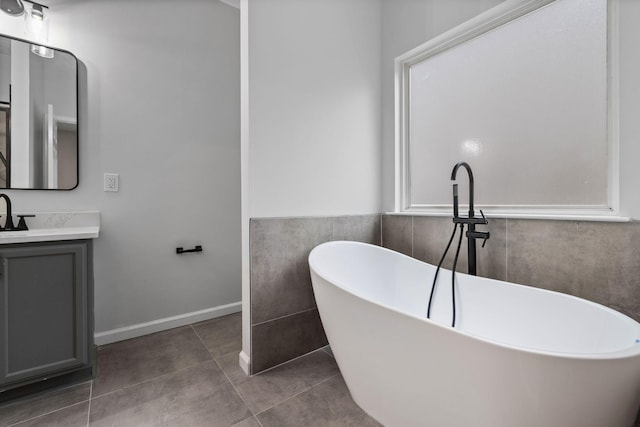 bathroom with tile patterned flooring, vanity, and a tub to relax in