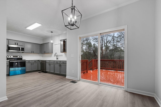 kitchen featuring crown molding, appliances with stainless steel finishes, gray cabinets, pendant lighting, and light hardwood / wood-style floors