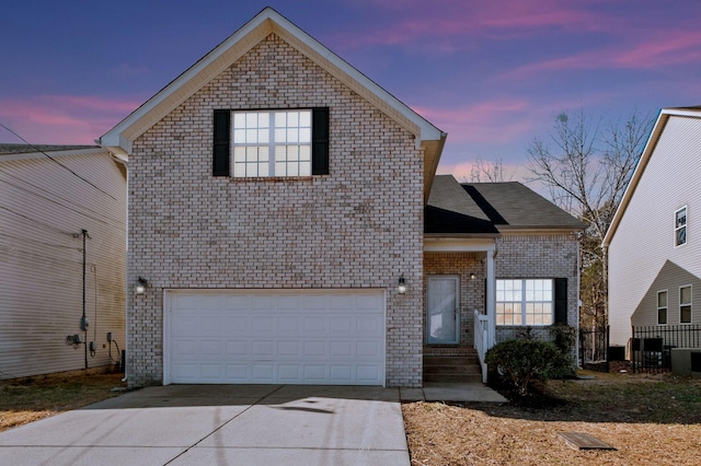 traditional home featuring driveway, brick siding, an attached garage, and fence