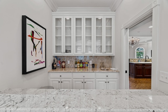 bar with sink, crown molding, white cabinetry, backsplash, and wood-type flooring