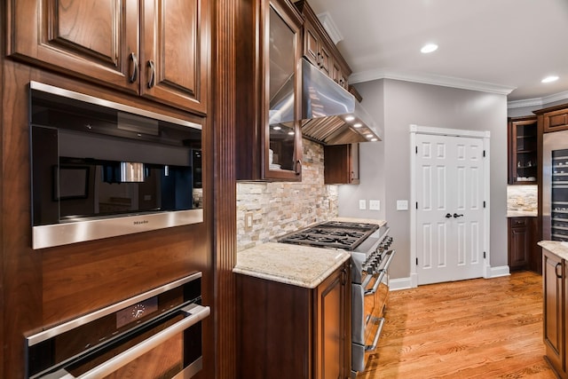 kitchen with ornamental molding, stainless steel appliances, light stone countertops, and exhaust hood