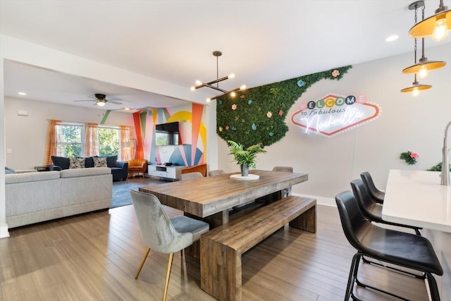 dining space featuring ceiling fan with notable chandelier and light hardwood / wood-style floors