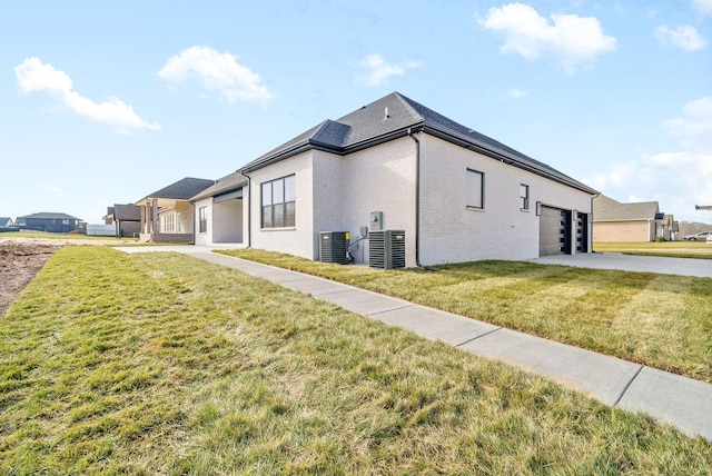 view of side of property with a garage, central AC unit, and a lawn