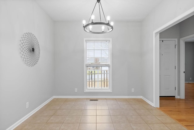 unfurnished dining area featuring an inviting chandelier and light tile patterned floors