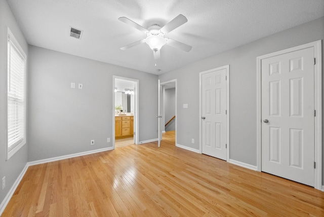 unfurnished bedroom featuring multiple windows, light hardwood / wood-style flooring, and ensuite bathroom