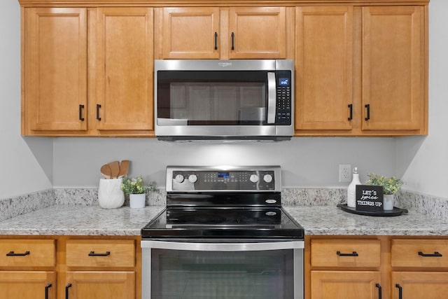 kitchen with appliances with stainless steel finishes and light stone counters