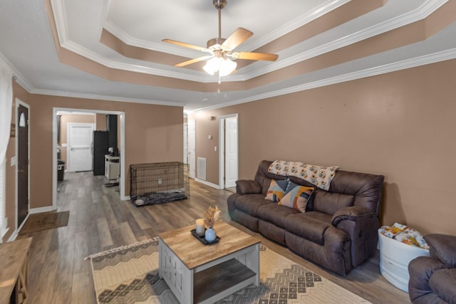 living room featuring dark hardwood / wood-style flooring, crown molding, a raised ceiling, and ceiling fan