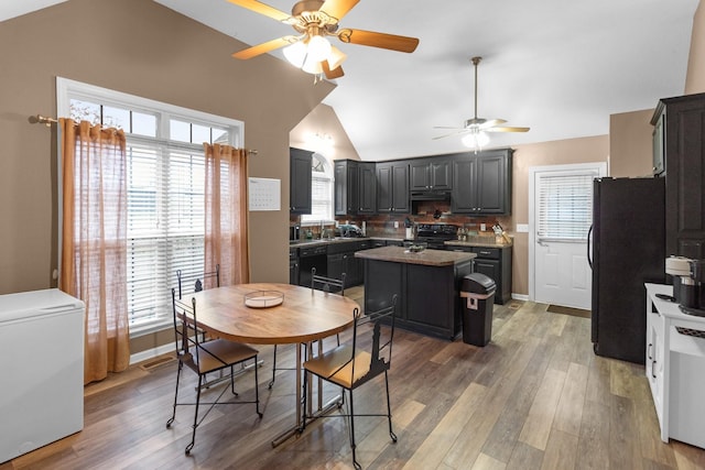 kitchen featuring vaulted ceiling, a kitchen island, hardwood / wood-style floors, sink, and black appliances