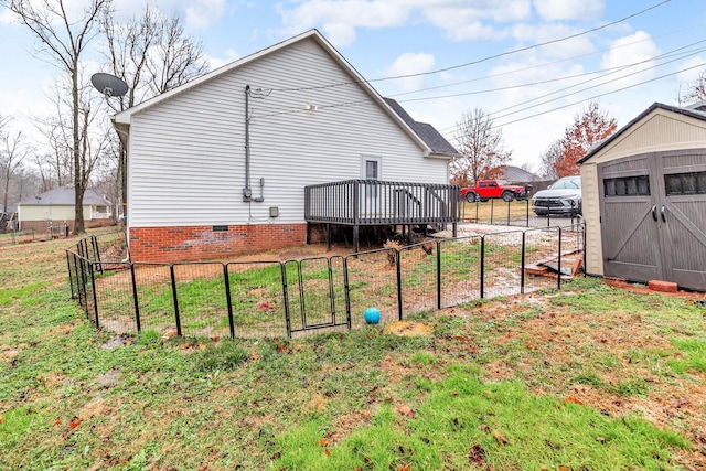 rear view of house featuring a yard, a deck, and a storage shed