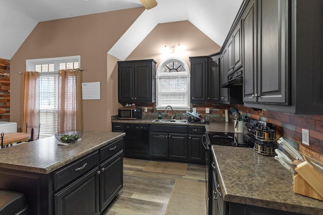 kitchen featuring vaulted ceiling, a kitchen island, sink, black appliances, and a healthy amount of sunlight