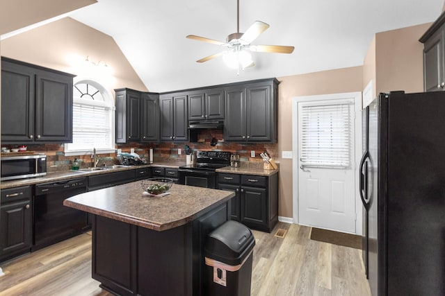 kitchen featuring sink, a kitchen breakfast bar, a center island, black appliances, and vaulted ceiling