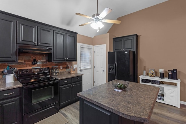 kitchen with black appliances, light hardwood / wood-style floors, a kitchen island, decorative backsplash, and vaulted ceiling