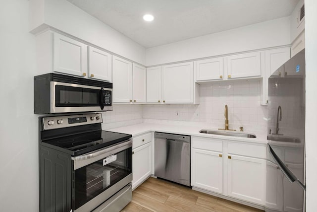 kitchen with stainless steel appliances, sink, white cabinets, and backsplash