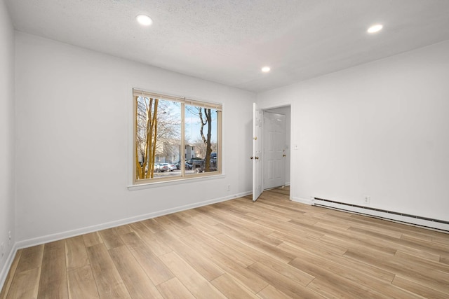 empty room with light hardwood / wood-style floors and a textured ceiling