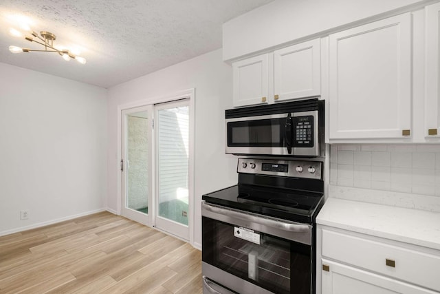 kitchen featuring white cabinets, decorative backsplash, light stone counters, light hardwood / wood-style floors, and stainless steel appliances