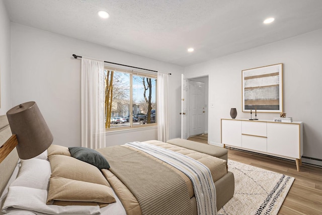 bedroom with a textured ceiling and light wood-type flooring