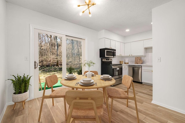 dining space featuring a chandelier, light hardwood / wood-style floors, and a textured ceiling