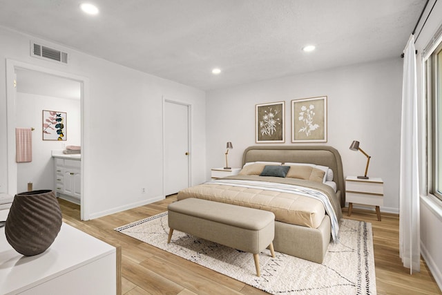 bedroom with ensuite bathroom and light wood-type flooring