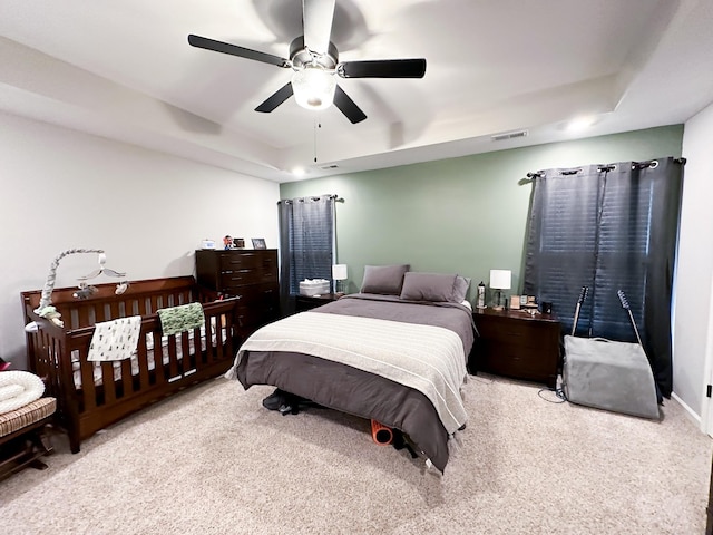 bedroom featuring ceiling fan, light colored carpet, and a raised ceiling