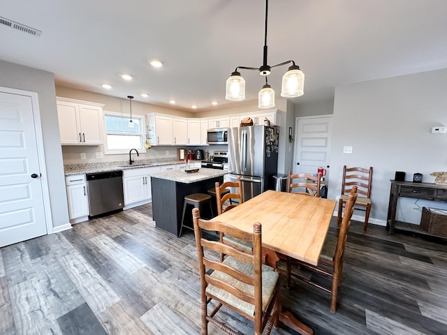 kitchen featuring pendant lighting, sink, stainless steel appliances, and a center island