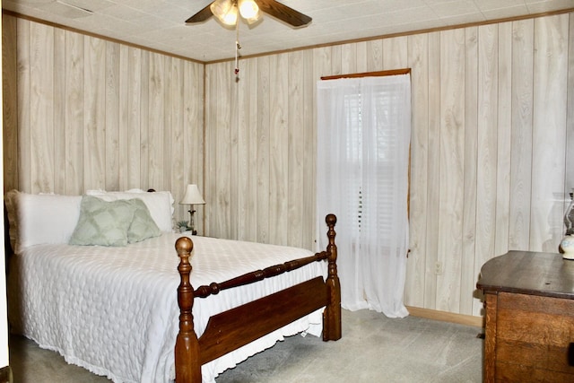 bedroom featuring ceiling fan, ornamental molding, carpet floors, and wooden walls