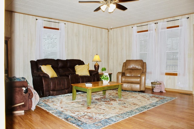 living room featuring ceiling fan, wood-type flooring, and wood walls