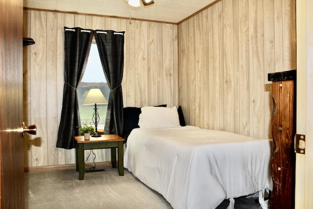 bedroom with ornamental molding, wooden walls, and carpet floors