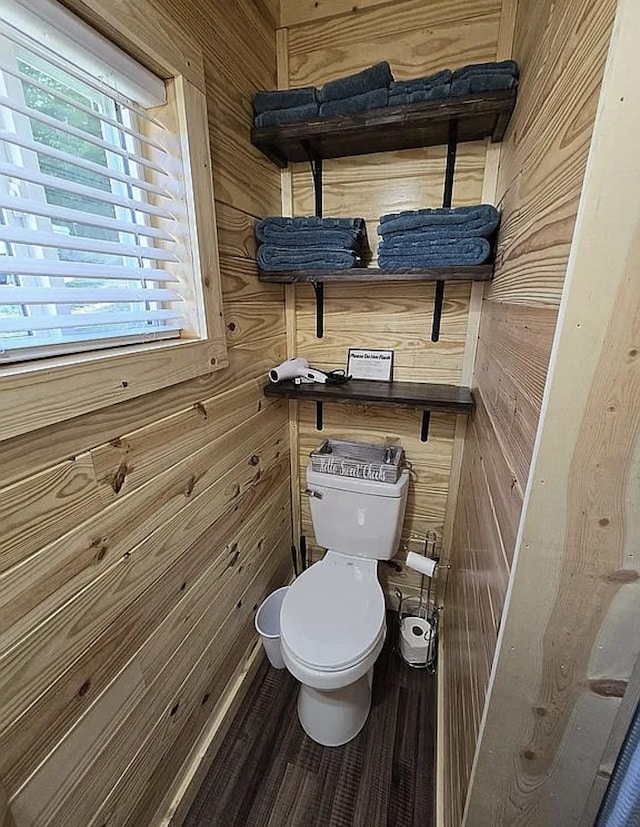 bathroom with hardwood / wood-style flooring, wooden walls, and toilet