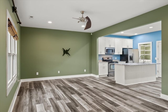 kitchen featuring an island with sink, appliances with stainless steel finishes, white cabinets, and light hardwood / wood-style floors