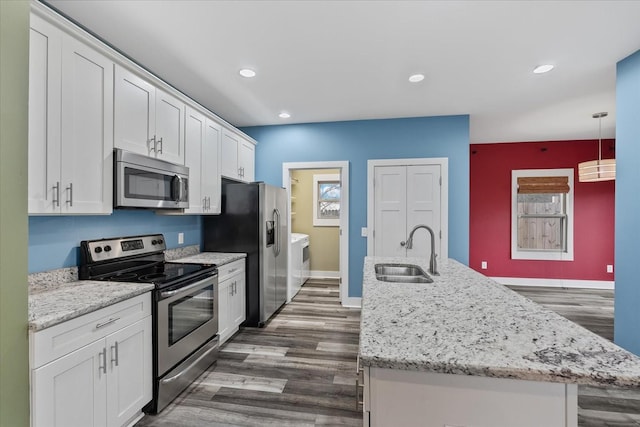 kitchen with pendant lighting, sink, appliances with stainless steel finishes, independent washer and dryer, and white cabinets