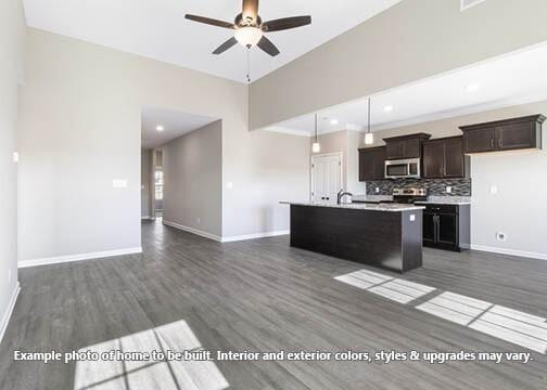 kitchen featuring decorative light fixtures, an island with sink, backsplash, ceiling fan, and dark wood-type flooring