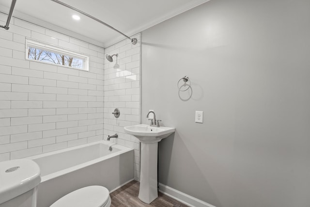 full bath featuring baseboards, toilet, wood finished floors, tub / shower combination, and a sink