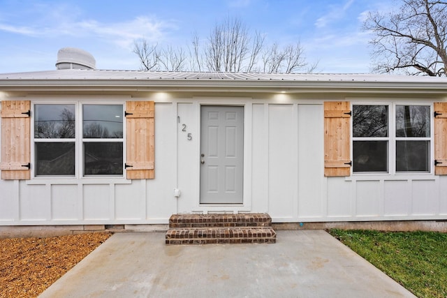 property entrance featuring crawl space, a patio area, metal roof, and board and batten siding