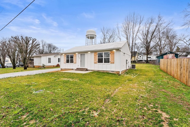 view of front of home with central AC unit, metal roof, fence, board and batten siding, and a front yard