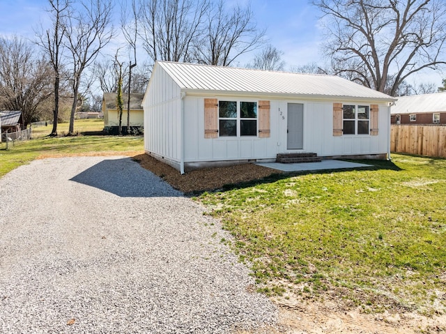 view of front of home featuring driveway, metal roof, board and batten siding, and a front yard