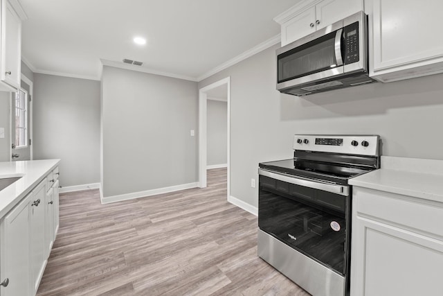 kitchen featuring stainless steel appliances, white cabinetry, light countertops, ornamental molding, and light wood-type flooring