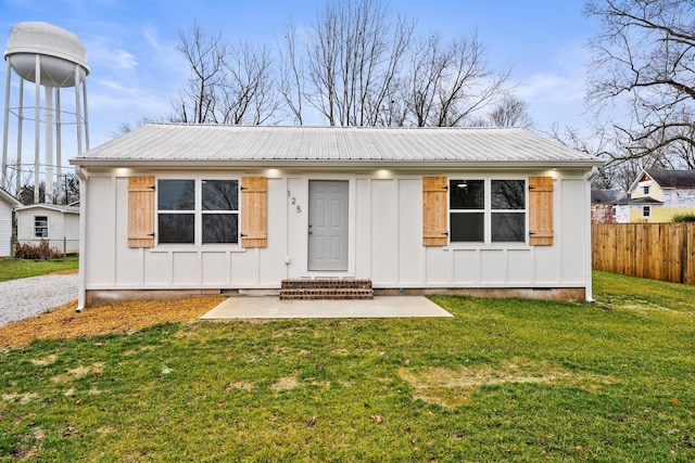 bungalow-style house with board and batten siding, a front yard, metal roof, and fence