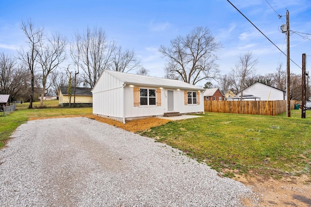 view of front of home featuring metal roof, fence, driveway, crawl space, and a front lawn